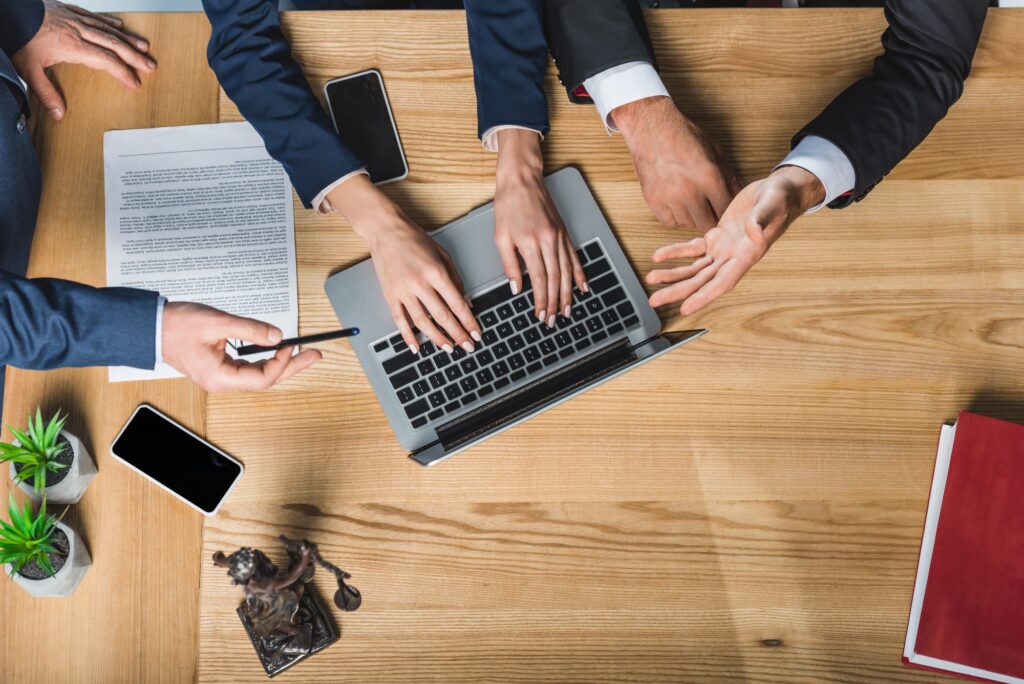 cropped shot of lawyers working on laptop together during meeting